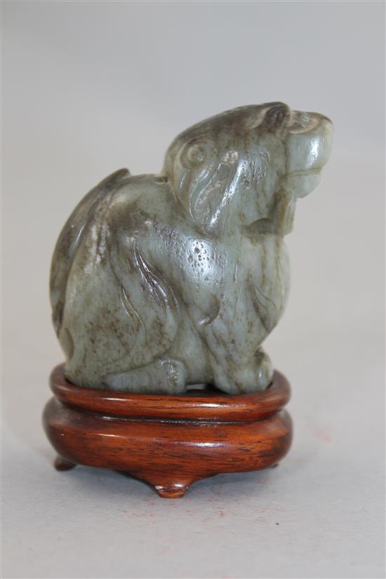 A Chinese pale grey and black jade carving of a lion-dog, Ming dynasty, 6cm., wood stand